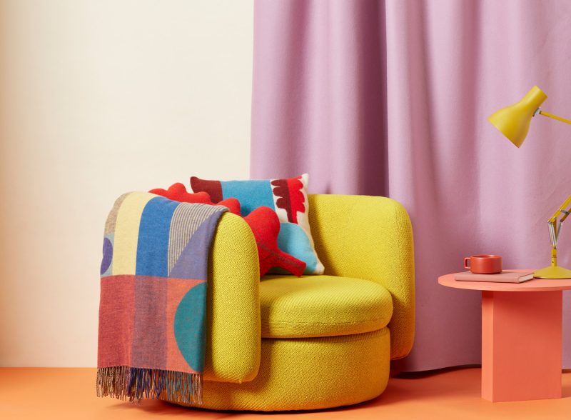 donna wilson abstract knitted cushion in blues and reds on chair