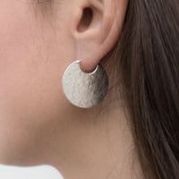 Silver disc hoop textured earrings on model.
